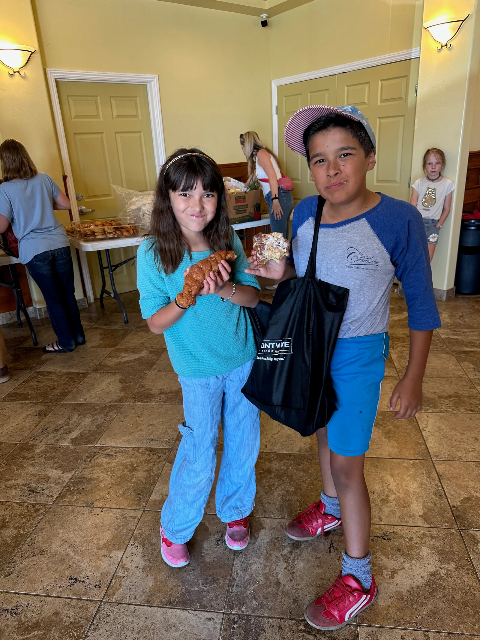 Two smiling kids holding fresh pastries at Harvest of Hope 2025
